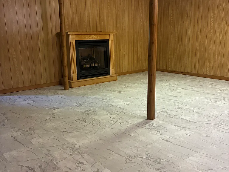 Spacious finished basement area featuring a gas fireplace, easy-care vinyl flooring, and flexible additional living space.