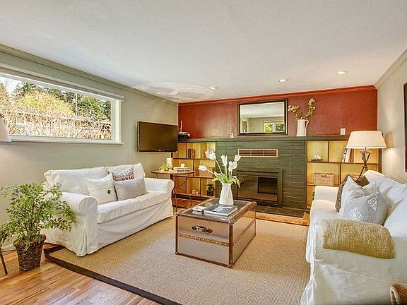 Living room with newly refinished hardwood floors, built in shelves and wood burning fireplace.