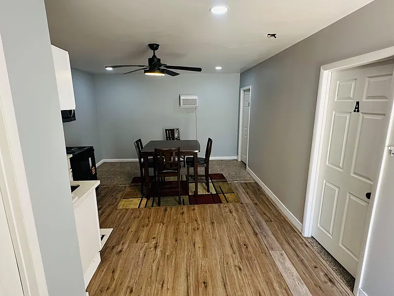 Open dining area with a four-seat table, ceiling fan, and durable flooring, connecting seamlessly to the kitchen.