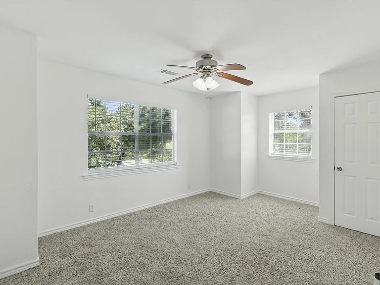 Carpeted spare room featuring a ceiling fan and baseboards