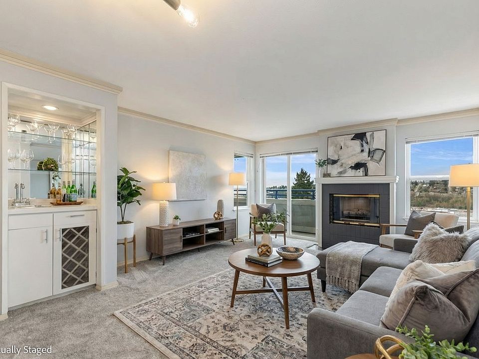 Living room has a gas fireplace, sliding door to a private deck, and views of Elliot Bay and the Olympic Mountains.
