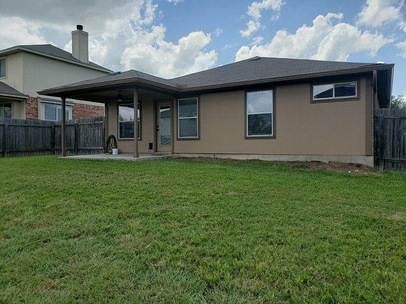 Fenced backyard with patio with fan.