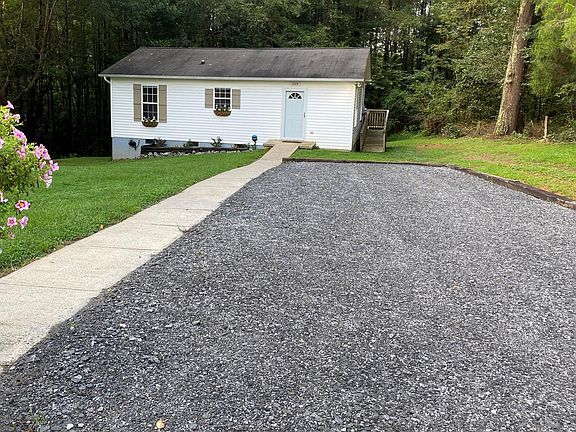 Paved driveway. Gravel parking spot. Privacy fence with hanging basket hook on left.
