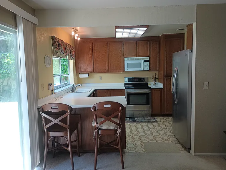 Kitchen includes window covering, stove, microwave, refrigerator, dishwasher and two chairs