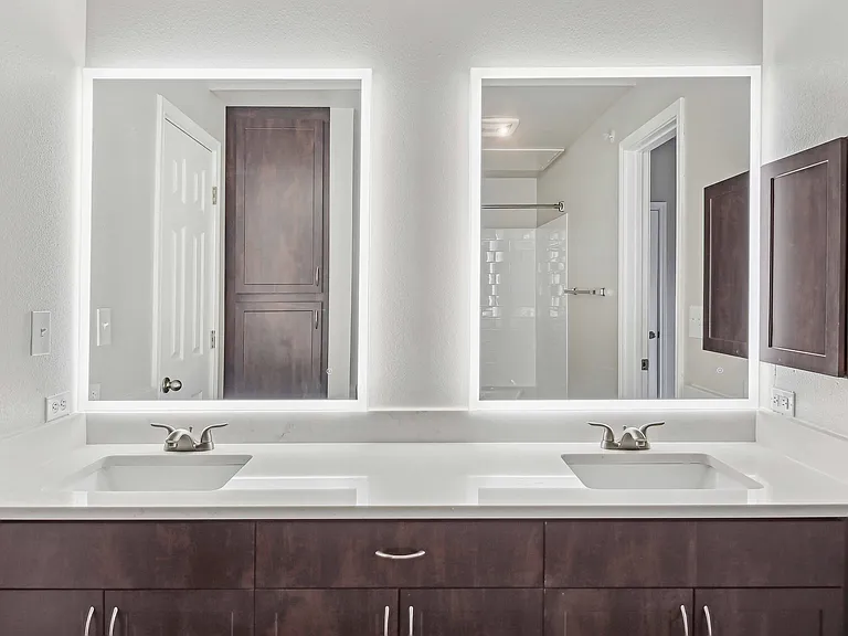 Upgraded bathrooms feature quartz countertops and backlit mirrors.