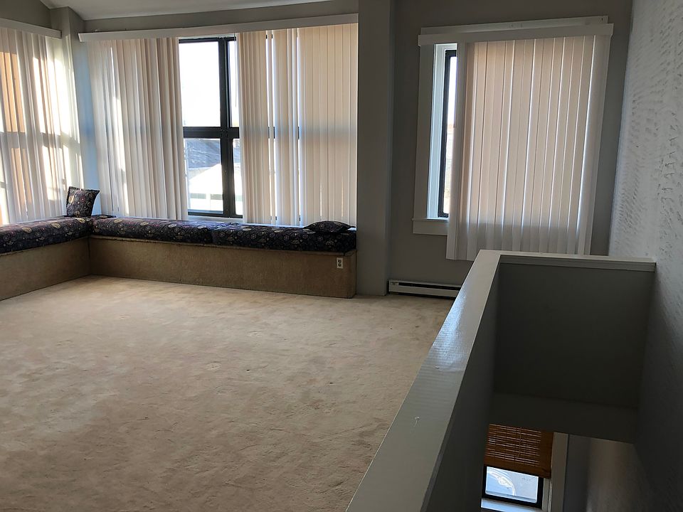 The west-facing great room, bathed in natural light features a LBFP, wall-to-wall carpeting, 15' ceiling and lovely window seats under a bank of windows