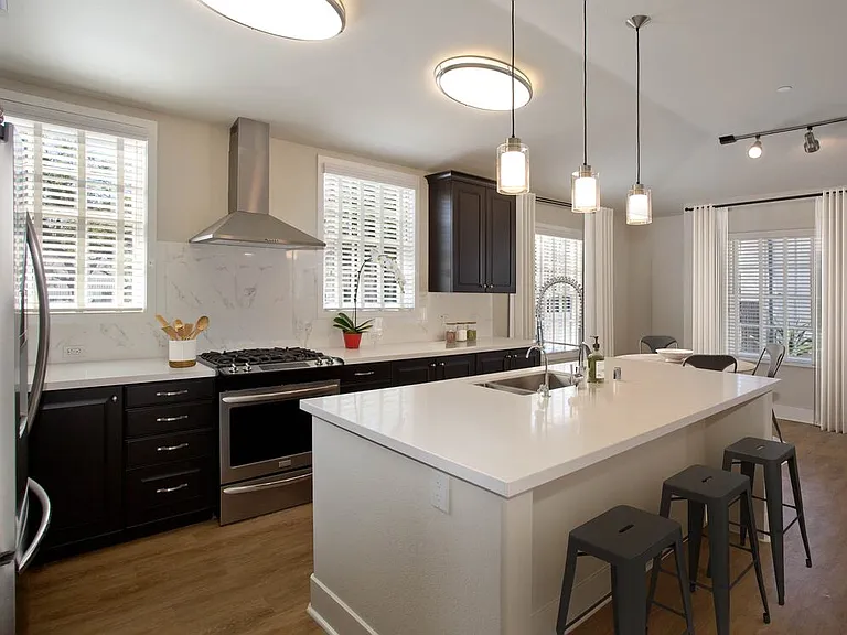 Kitchens with dark cabinetry, white quartz countertops, white tile backsplash, stainless steel appliances, and hard surface flooring