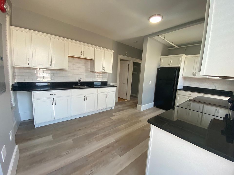 Large kitchen with black granite countertops on custom white cabinets, white subway tile backsplash and new appliances