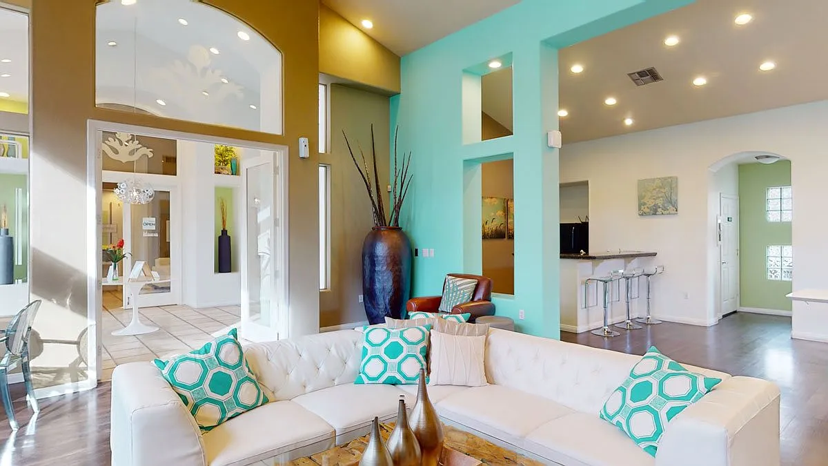 Modern living room with a white sectional sofa and teal accent wall.