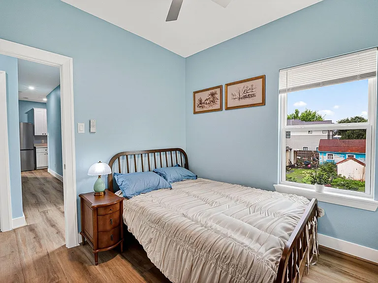 Private bedroom with a ceiling fan, large window, and space for a full/queen bed plus a nightstand.
