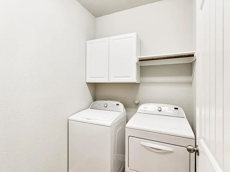 Dedicated laundry area featuring a white shaker-style wall cabinet and a built-in shelf