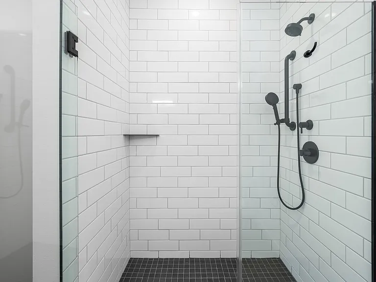 Modern glass-enclosed shower with sleek matte black fixtures and pristine white subway tiles. Modern glass-enclosed shower with sleek matte black fixtures and pristine white subway tiles.
