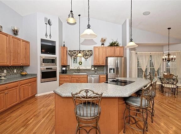 Hardwood floors, hard surface countertops, stainless appliances, large island with breakfast bar and cooktop. 42"cabinets compli