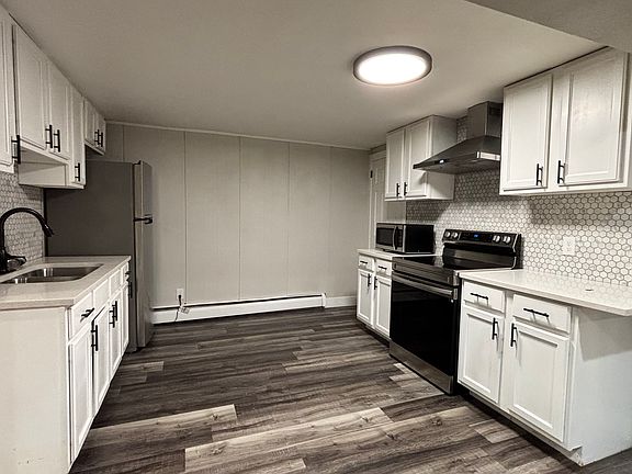 Open kitchen area with modern appliances and new hood vent