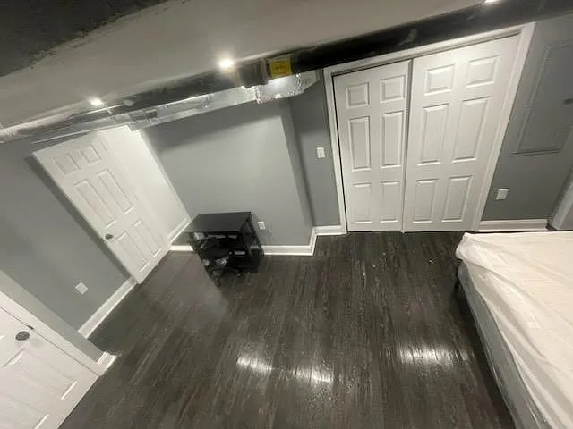 Finished room with dark wood-style flooring, recessed lighting, and double-door closets for convenient storage. - Chew Ave