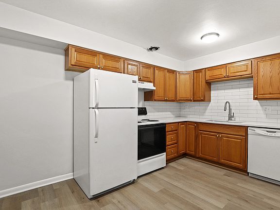 Bright and inviting kitchen with modern white appliances, elegant wooden cabinets, and sleek countertops. Ideal for culinary creativity.