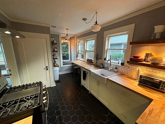 Open shelving to keep kitchen feeling open. Window seat and counter with stools. Newer gas stove and refrigerator.