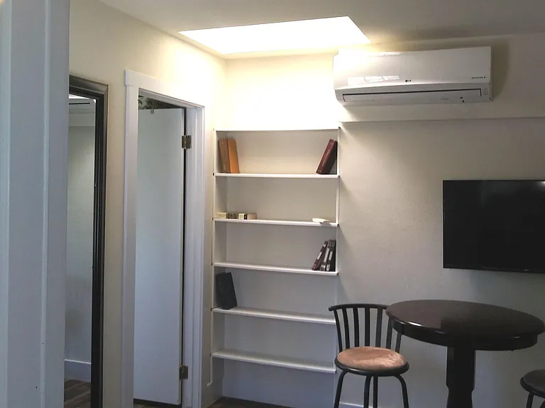View from front door showing bedroom door and wall backing closet of next door unit. Note skylight and air conditioner head. AC/heat is independently controlled by unit tenant.