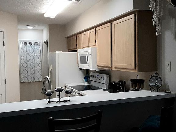 Kitchen breakfast bar, closet, and electric stove/oven, microwave, fridge/freezer. The washer/dryer combo is beyond the fridge. The pantry is beyond the closet.