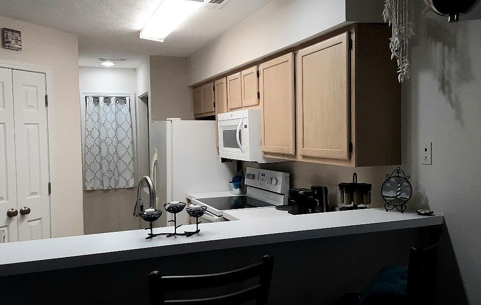 Kitchen breakfast bar, closet, and electric stove/oven, microwave, fridge/freezer. The washer/dryer combo is beyond the fridge. The pantry is beyond the closet.