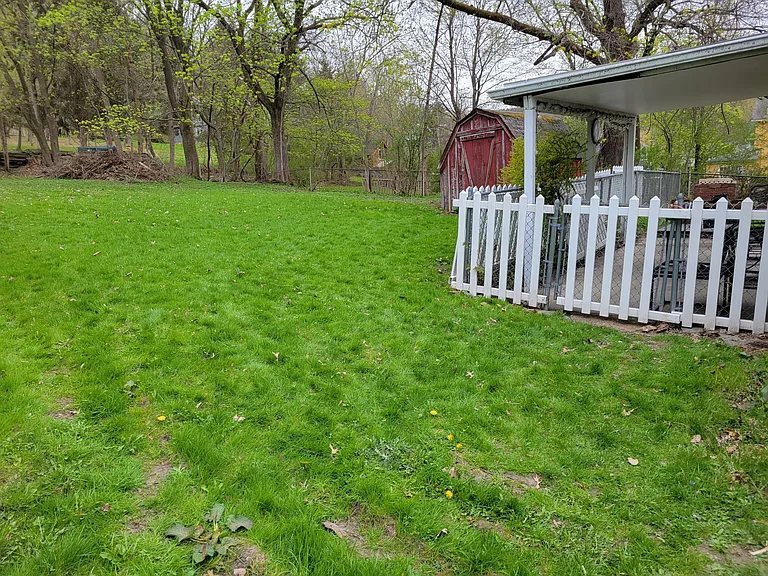 Covered and fenced patio (from kitchen door with doggie door) surrounded by large grassy back yard.