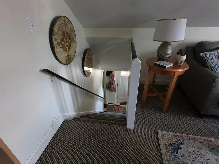 Living room (alternate view) with stairs leading down to kitchen and entrance.