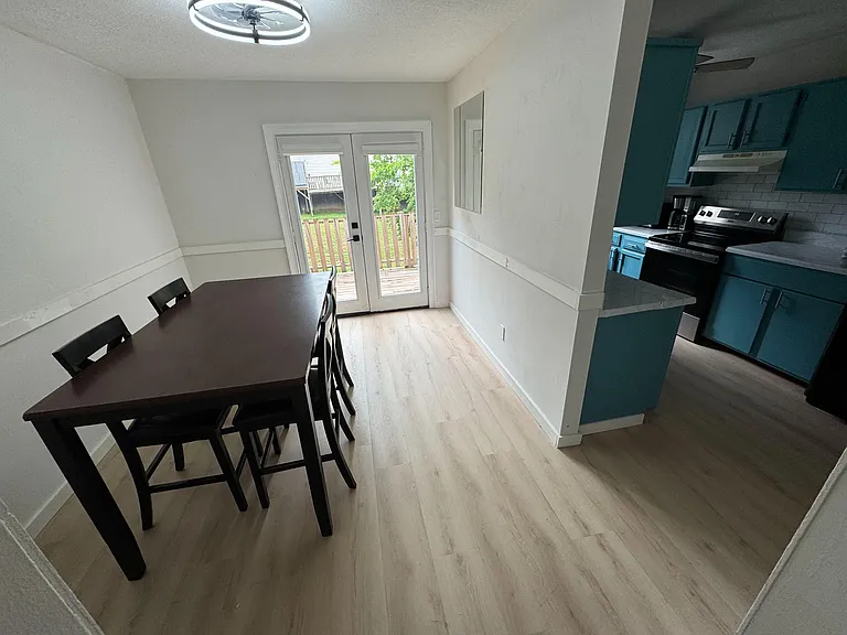 Dedicated dining area with a full table set, light flooring, and French doors leading to a backyard deck.