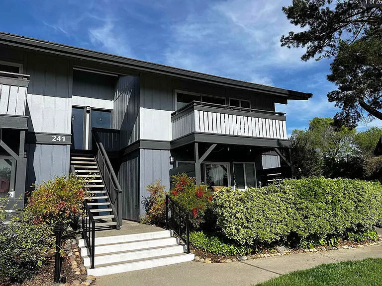 Apartment entrance surrounded by mature trees and well-maintained landscaping