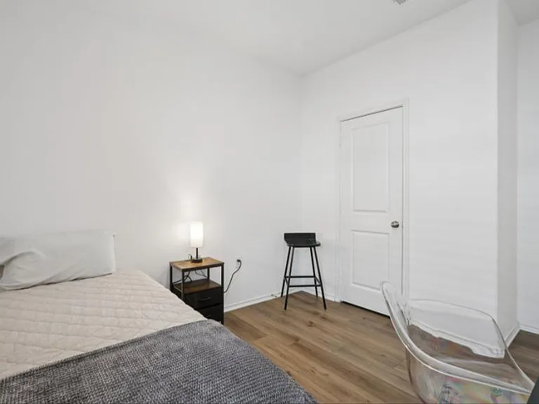 Private bedroom with wood-style flooring, a comfortable bed, and space for a desk or reading chair.