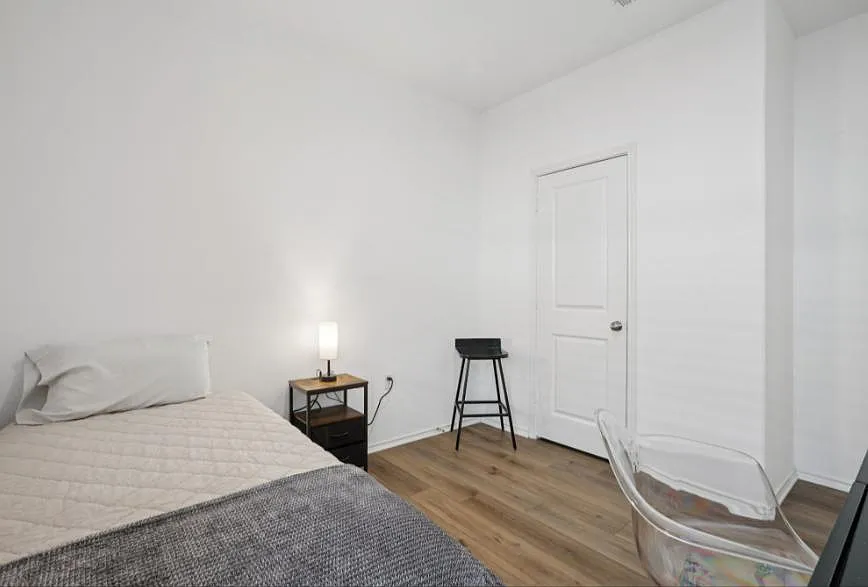 Private bedroom with wood-style flooring, a comfortable bed, and space for a desk or reading chair. - Berning Rd