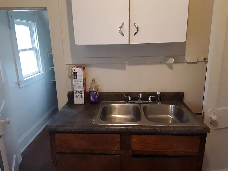 Sink and cupboard showing entry to small pantry