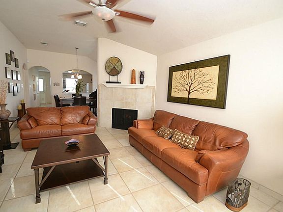 Spacious family room featuring tile floors, raised ceilings, ceiling fan with light fixture and a fi
