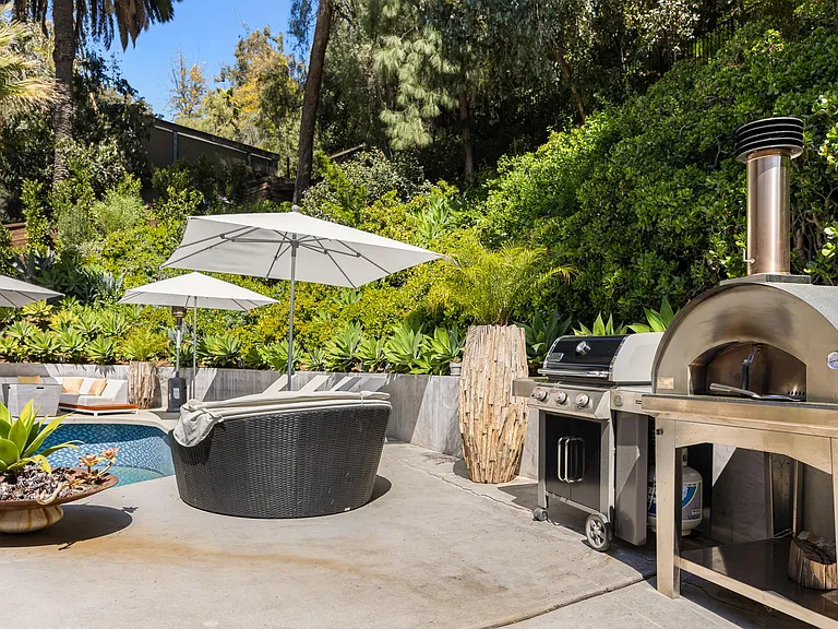 Wood-fired pizza oven and BBQ grill, perfect for outdoor feasts in the sun-kissed pool area.