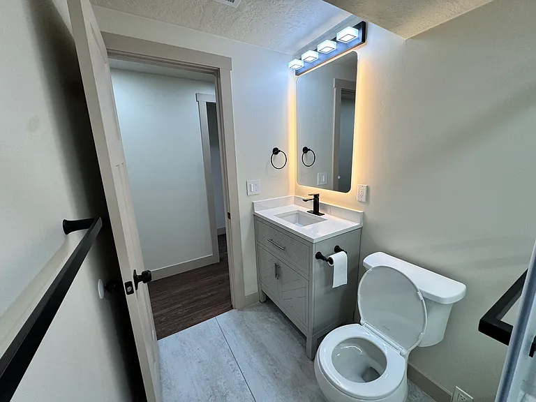 New bathroom featuring a modern vanity, LED-lit anti-fog mirror, and a tub/shower combo with sliding glass doors.