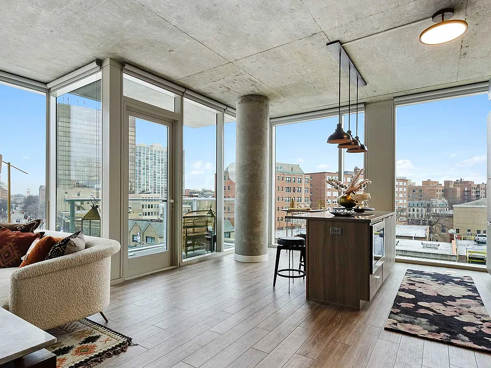 Expansive corner windows surround this open-concept apartment with neighborhood views, while the kitchen island and private balcony extend the possibilities for everyday living.