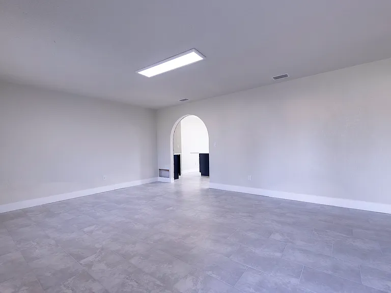 Living room view from front door entry. Archway leads to eat-in kitchen.
