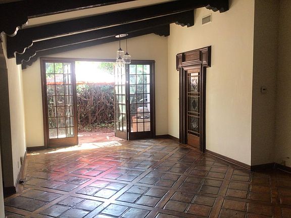 living room/dining room with wood beamed cathedral ceiling, french and stained glass doors, leading to outside patio wood and tile floors, massive fireplace