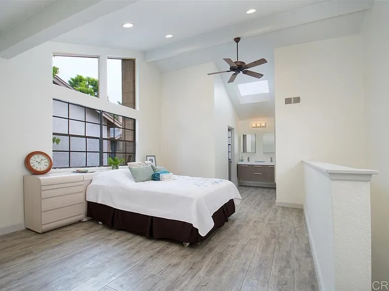This generously sized master bedroom within a 1000sqft condominium offers a tranquil and inviting atmosphere. The vaulted ceiling with its skylight creates a sense of openness and natural light, while the ceiling fan provides a gentle breeze.