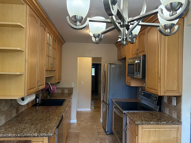 Beautifully upgraded galley kitchen - granite tops, all stainless steel appliances. Custom wine rack and end cap racks. Illuminated cabinet and black designer stone sink. Dishwasher. Brand new gas stove, microwave and refrigerator. Custom chandeleiir.