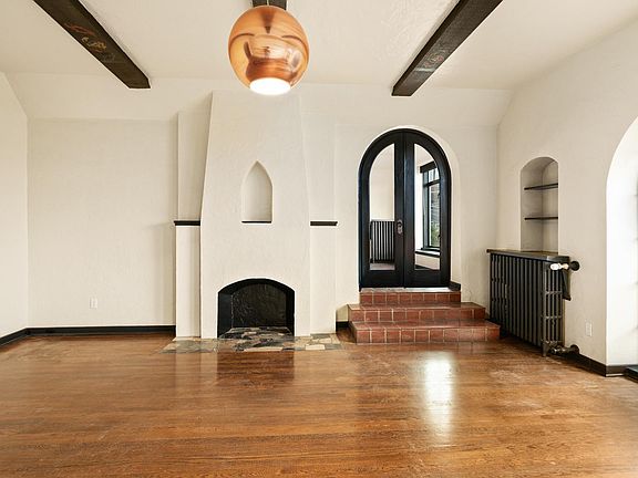 Living room with arched entry into the second bedroom. Faux fireplace.