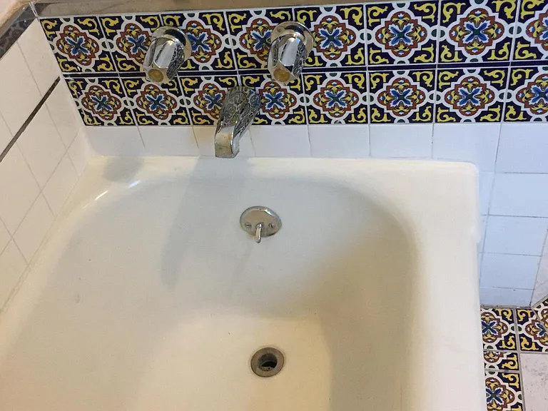 Large separate bathtub with custom Spanish deco tile.