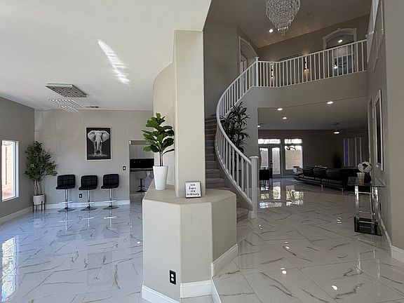 Expansive foyer view showcasing the sweeping staircase, chandelier, loft overlook, and open living spaces beyond.