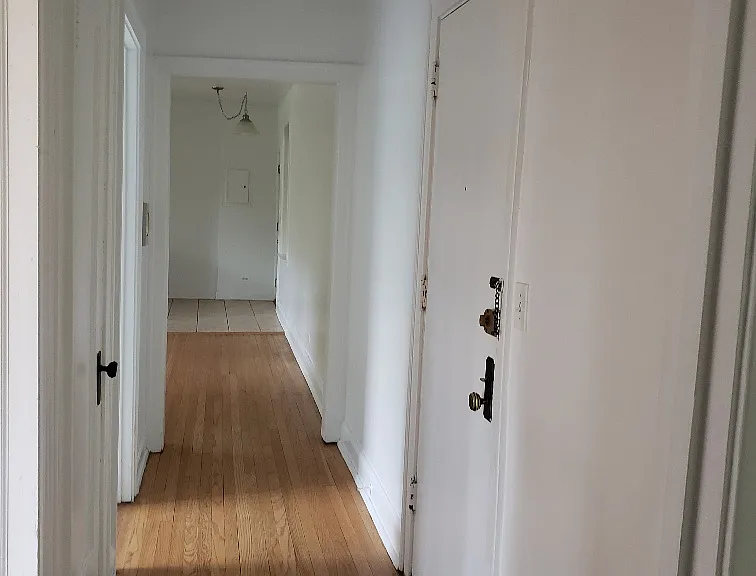 Hardwood floors in hallway lead, entry door on right, view towards kitchen