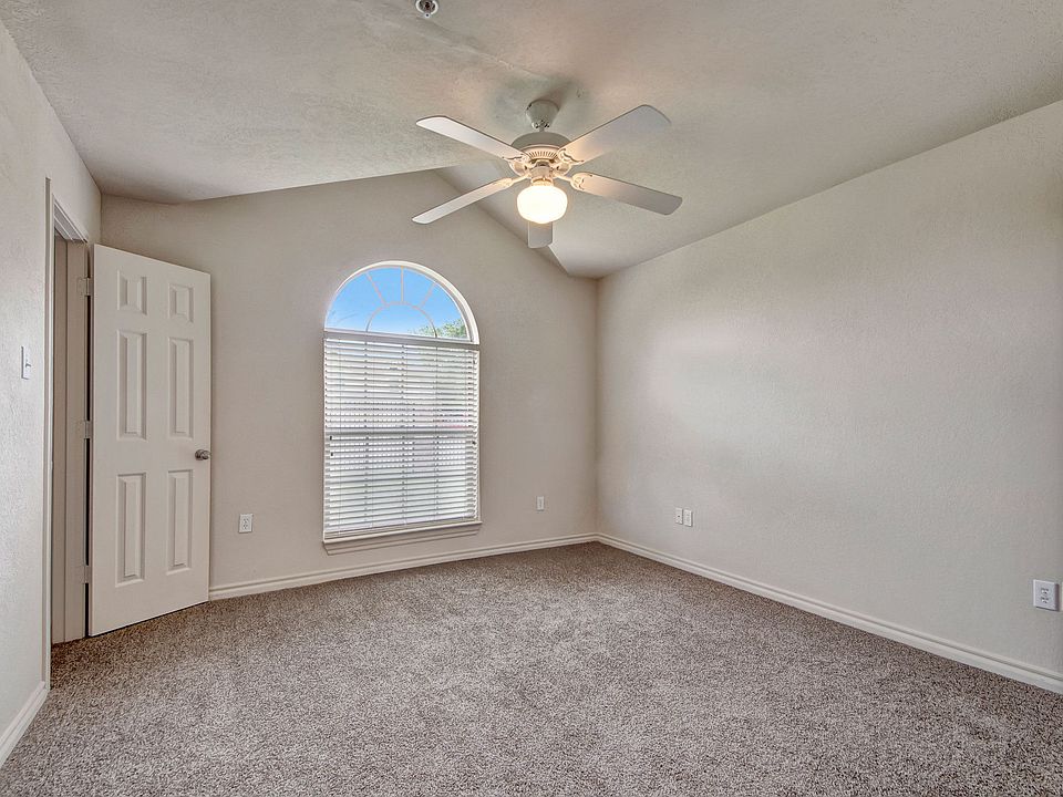 A large bedroom with a ceiling fan and wide window