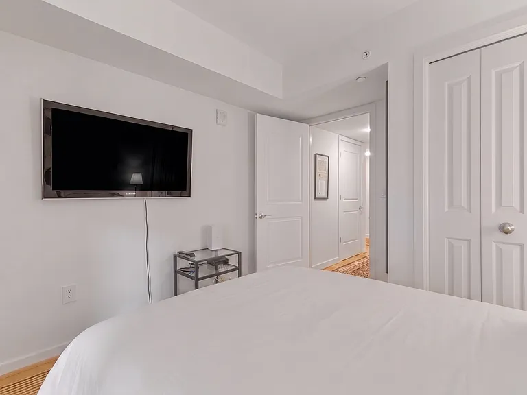 Unwind with your favorite shows from bed with the wall-mounted flat-screen TV in this clean, modern room.