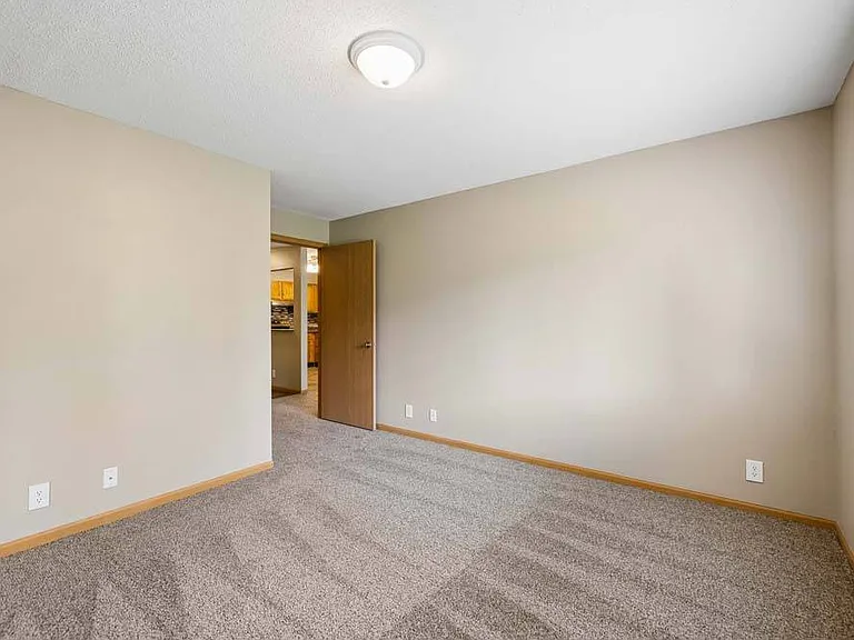 Filled with natural light and a calming neutral palette, this inviting bedroom offers a peaceful retreat with plenty of room to make it your own.