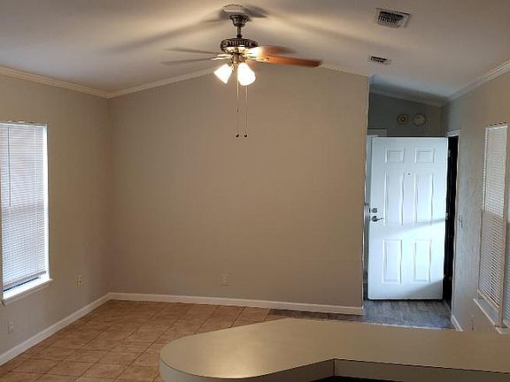 Open concept view of living room from kitchen area. Front door open in rear.