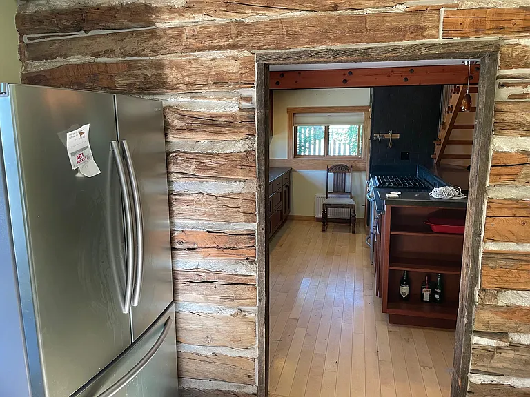 Coming in back door to kitchen you find shelving, a window and fridge.