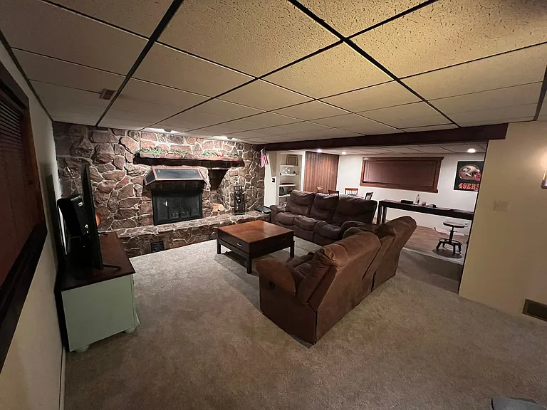 Basement level cozy family room with wood burning fireplace.