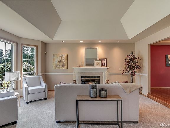 This luxurious living room features a gorgeous ceiling detail, picture windows, a wood burning fireplace and views into the dining room.